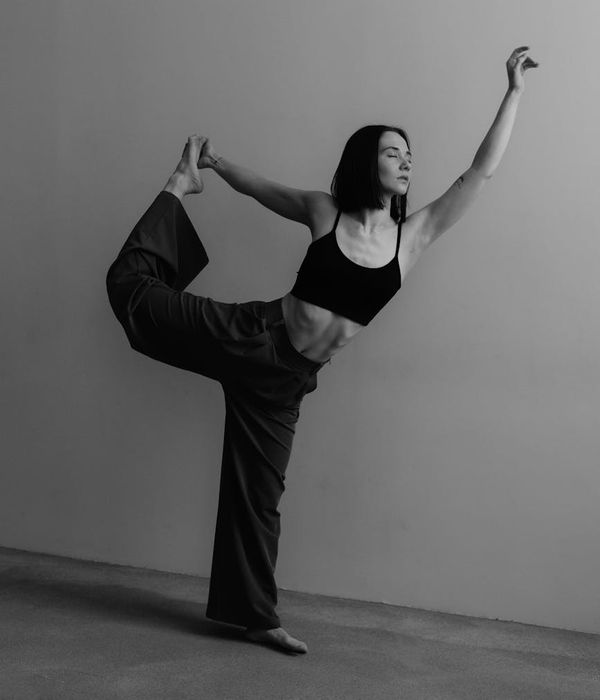 Woman in a graceful yoga pose against a minimal background.